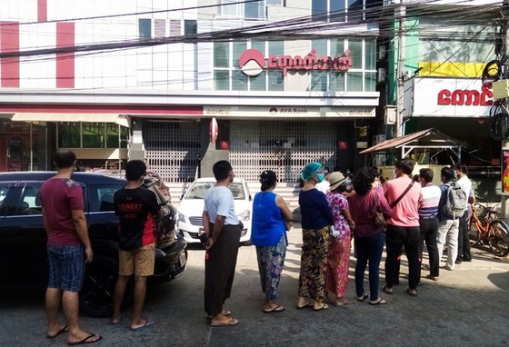 Người dân xếp hàng trước một chi nhánh ngân hàng ở Yangon để chờ rút tiền. Ảnh: Reuters.