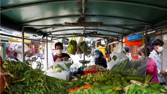 Người dân mua rau từ một xe bán dạo khi nhiều chợ tươi sống đóng cửa 14 ngày, ở Phnom Penh, Campuchia, ngày 17/4/2021. Photo: Cindy Liu / Reuters