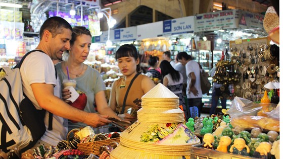 Du khách nước ngoài đang chọn mua các mặt hàng thủ công mỹ nghệ, quà lưu niệm tại chợ Bến Thành   Ảnh: Gia Hân