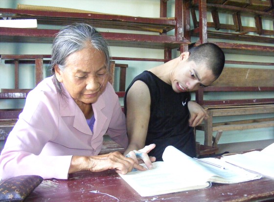 Bà giáo Nguyễn Thị Thông đang dạy cho cháu Nguyễn Văn Nguyên 