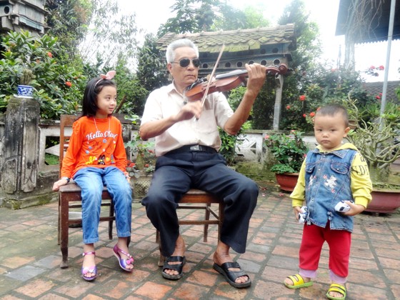 Chú Nguyễn Đăng Khoa ngồi kéo violon trước sân nhà