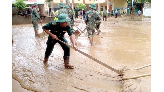 Bộ đội Biên phòng tỉnh Nghệ An giúp dân dựng lại nhà, dọn dẹp trường lớp. Ảnh: DUY CƯỜNG