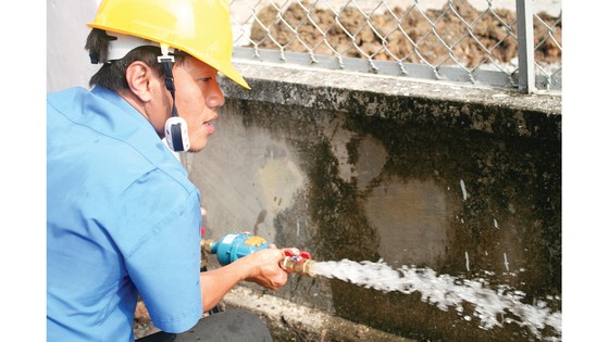 Nhân viên Tổng Công ty Cấp nước Sài Gòn kiểm tra chất lượng nước tại đồng hồ của khách hàng. Ảnh: MINH PHONG