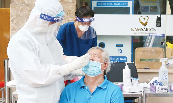 Nhân viên y tế Bệnh viện Đa khoa Quốc tế Nam Sài Gòn lấy mẫu xét nghiệm cho người dân. Ảnh: HOÀNG HÙNG