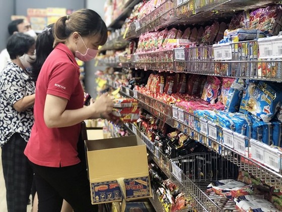 Nhân viên nhãn hàng bổ sung thêm hàng hóa thiết yếu lên kệ tại siêu thị ở TP Hồ Chí Minh. (Ảnh: Mỹ Phương - TTXVN.)