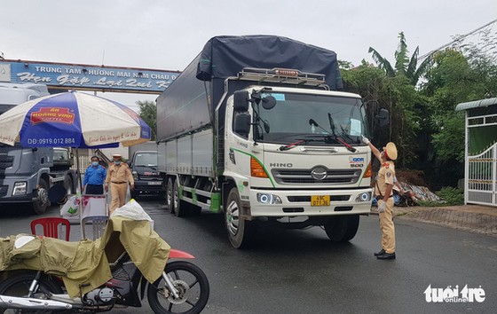 Công an huyện Châu Phú kiểm tra giấy xét nghiệm âm tính COVID-19 của một tài xế xe tải - Ảnh: BỬU ĐẤU