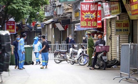 Lực lượng công nhân vệ sinh thu dọn rác thải tại khu vực phong tỏa phường Phú Đô, quận Nam Từ Liêm (Hà Nội). (Ảnh: Tuấn Đức/TTXVN)