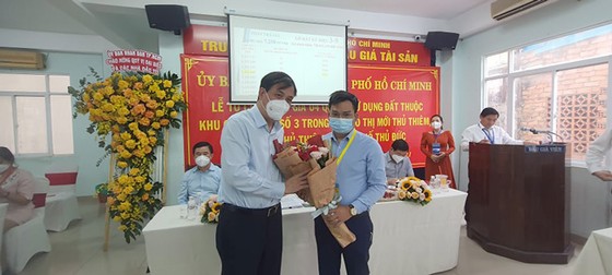 Ông Lê Hòa Bình, Phó chủ tịch UBND TP, trao hoa chúc mừng Công ty Bình Minhtrúng đấu giá lô đất 3-9.