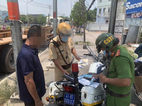 Lực lượng xử phạt một tài xế dừng đỗ ngay tại vòng xoay Phú Hữu. Ảnh: CHÍ THẠCH 