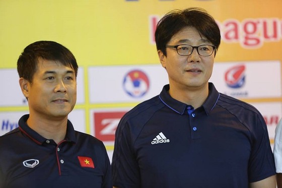 HLV Hữu Thắng (trái) và đồng nghiệp Hwang sun-Hong (Hàn Quốc) trao đổi về trận đấu