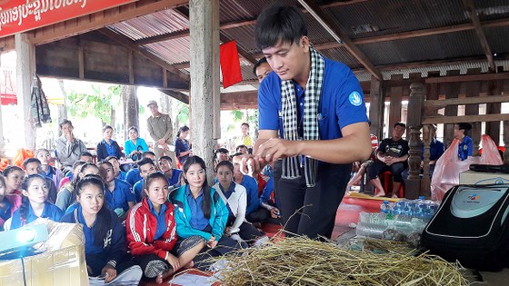 Chiến sĩ tình nguyện Mùa hè xanh tập huấn cách trồng nấm cho người dân,  thanh niên nước bạn Lào. Ảnh: THU HƯỜNG