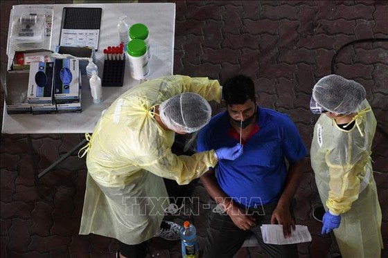 Nhân viên y tế lấy mẫu xét nghiệm Covid-19 cho người dân tại Singapore. Ảnh: AFP/TTXVN