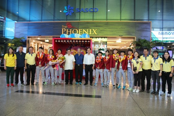 Lãnh đạo LĐBĐ TPHCM, Trung tâm thể thao Quận 1 cùng đại diện đội nữ TPHCM chúc mừng cô trò HLV Kim Chi tại sân bay Tân Sơn Nhất. Ảnh: HỮU THỊNH