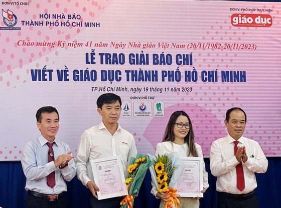 Nhà báo Dương Vũ Thông, Phó Chủ tịch thường trực Hội Nhà báo TPHCM (ngoài cùng bên trái) và Nhà báo Nguyễn Thanh Tú, Tổng Biên tập Tạp chí Giáo dục TPHCM tặng hoa và Giấy chứng nhận cho 2 tác giả đoạt giải Nhì