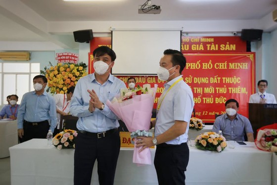 Ông Lê Hòa Bình, phó chủ tịch UBND TP, trao hoa chúc mừng đơn vị trúng đấu giá lô đất 3-5 - Ảnh: NHẬT THỊNH