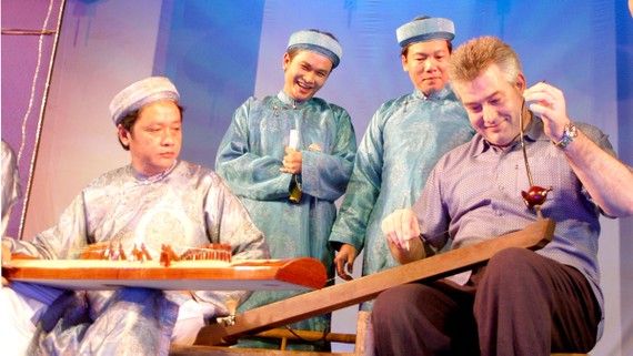 Du khách nước ngoài thích thú chơi thử đàn bầu. Ảnh: AN DUNG