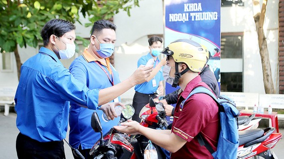Đo thân nhiệt sinh viên ngay cổng ra - vào trường. Ảnh: THANH HÙNG 