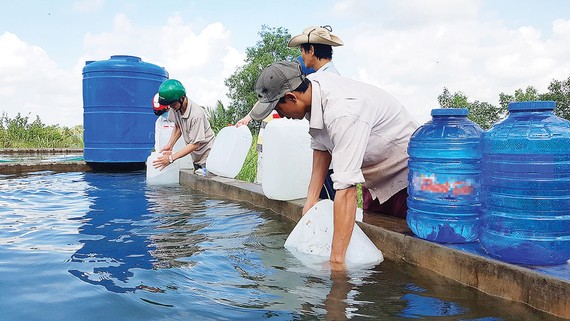 Người dân xã Thạnh Phú Đông, huyện Giồng Trôm, tỉnh Bến Tre lấy nước ngọt từ bể chứa về sử dụng. Ảnh: BÙI ANH TUẤN