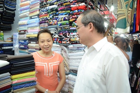 市委書記阮善仁看望安東市場，並詢問了某一布販的生意情況。（圖源：ĐL）