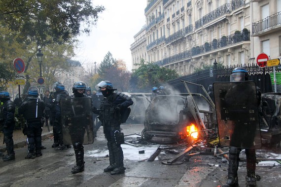 防暴警察在巴黎市中心正在燃燒的車輛前嚴密警戒。（圖源：互聯網）