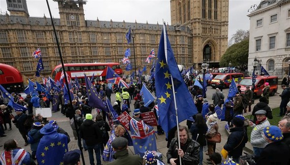 英國倫敦民眾在議會大廈外揮舞旗幟和標語牌。（圖源：新華社）