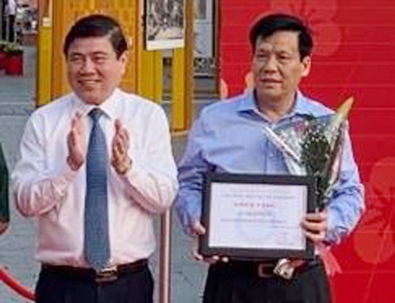 市人委會主席阮成鋒(左)向《西貢 解放報》副總編輯、華文《西貢解放日 報》主編阮玉英(紅藍)頒獎。