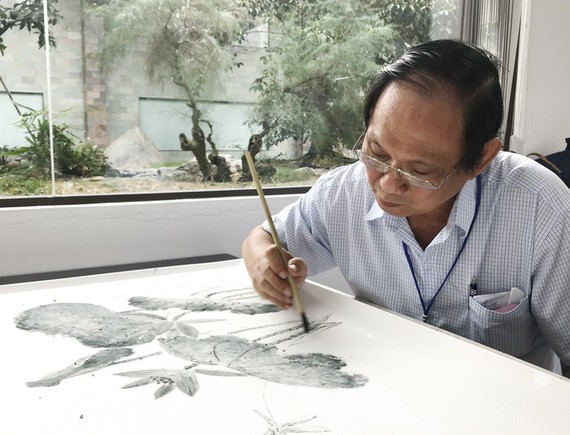 張漢明在瓷板上繪畫。 