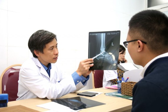 震傷矯形院副院長阮孟慶醫生為一名傷者查看踝關節 X光片。