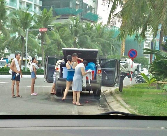 一家約5至7人在峴港海灘路邊停車並當街用淡水沖洗。（圖源：互聯網）