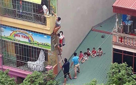 附近許多居民與學生家長在幼兒園外搭梯爬過隔壁住房頂層，進入幼兒園四樓並從前面露台送學生到地面。（圖源：玉玄）