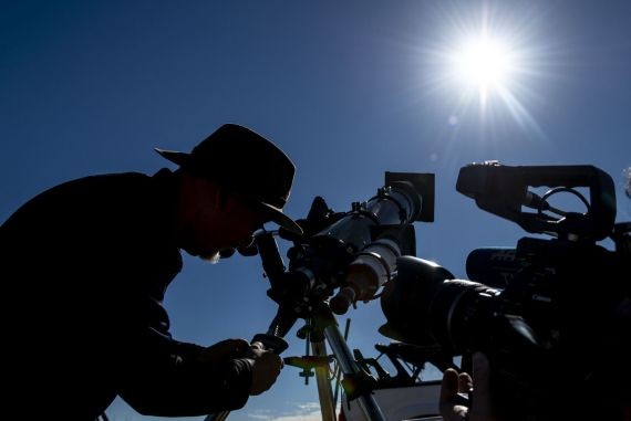 當地時間7月1日，智利聖地亞哥以北的阿塔卡馬沙漠一處天文營地的入口處，遊客帶著特制的眼鏡嘗試觀看日食。（圖源：AFP）