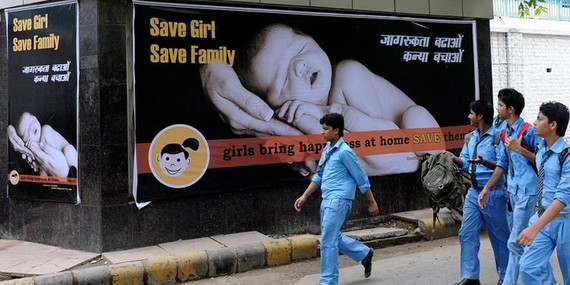 印度男生於2010年7月9日走過新德里的一幅鼓勵女孩誕生的宣傳海報。（圖源：AFP）
