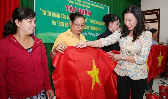 市越南祖國陣線委員會副主席趙麗慶（右一）將國旗贈予芹耶縣漁民。（圖源：勞動者報）