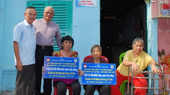 本報編委兼編輯部主任范興(左)和華企呂永雄在轉 交儀式上向戶主象徵贈送贊助修建溫情屋經費數目牌子。