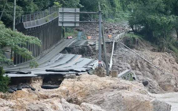日本九州熊本縣蘆北町球磨川旁一條道路，因河水暴漲淘空路基而中斷。（圖源：AFP）