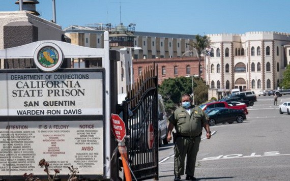 一名加州懲戒及改造局（CDCR）的官員戴著口罩站在聖昆廷州立監獄的前門。（圖源：Getty Images）