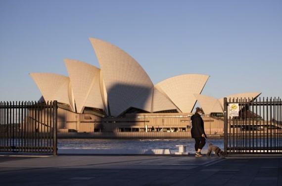 一名婦女在澳大利亞悉尼的悉尼歌劇院附近遛狗。（圖：新華社）