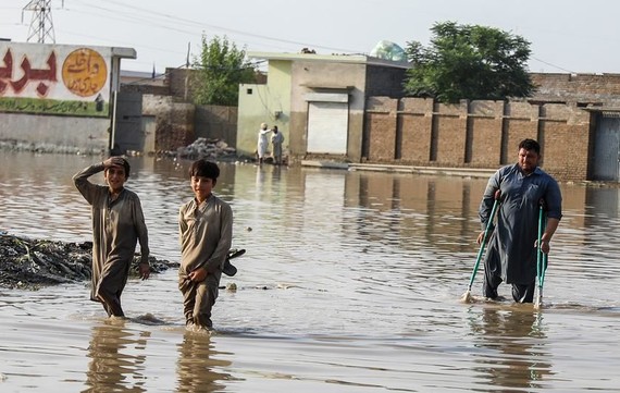 在巴基斯坦开伯尔-普赫图赫瓦省受灾最严重的地区之一瑙谢拉卡兰，两个男孩和一名拄着拐杖的男子穿过被洪水淹没的街道。（图：联合国）