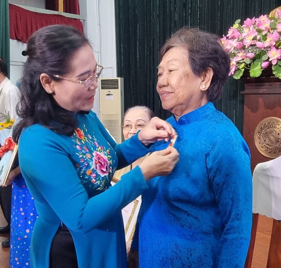 市委副书记、市人民议会主席阮氏丽向华人党员李金梅别上55年党龄纪念章。