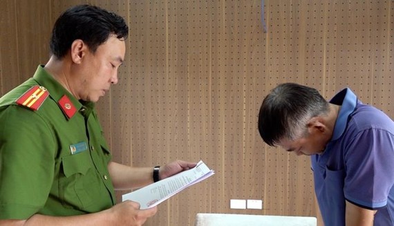 执法警员向犯罪嫌疑人黎文长宣读逮捕令。（图：安江报）