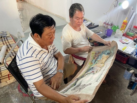 黄坤隆艺人（右）向老同学朱学光先生（左）介绍壁画稿。