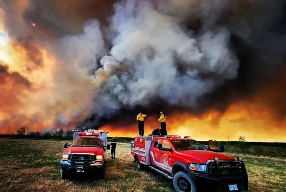 在加拿大不列颠哥伦比亚省圣约翰堡附近的一场野火中，消防员本月14日站在坎卢普斯消防救援货车上。（图：路透社）