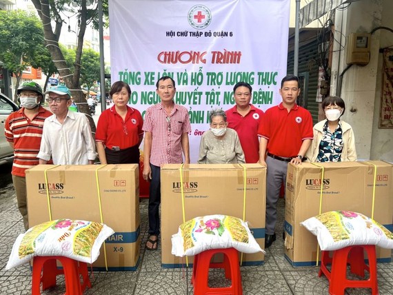红十字会主席黎氏宝庄（左三）、副主席张世强（右二）与热心人士陈弟（左四）等向残疾人士赠送轮椅与大米。