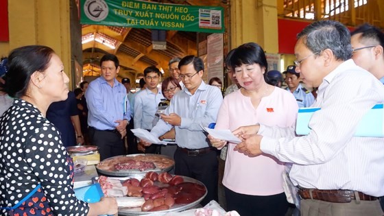市人民議會專責監察團正檢查濱城市場豬肉攤的豬肉來源證明書。（圖片來源：互聯網）