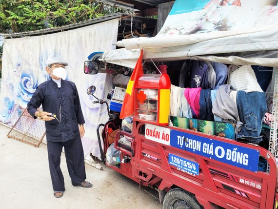 阮文四在堆滿舊衣服的車子旁邊。