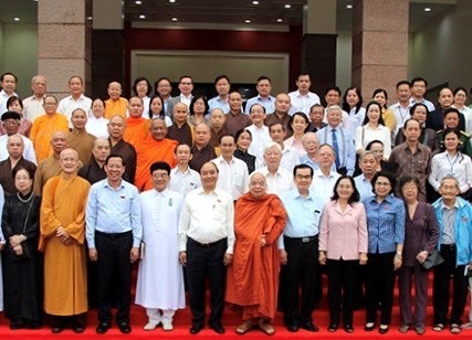 國家主席阮春福（前排左五）和市領導與諸位具威信華人同胞、 各宗教代表等合照留念。（資料圖）