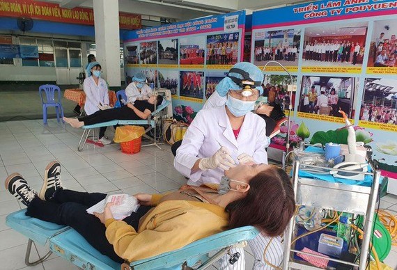 醫護人員在“為勞動者健康”盛會上給越南寶元有限責任公司工人們檢查體康。（圖：H. Đào）