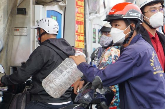 一名男性帶著塑料瓶在一加油站排隊等候購買汽油。（圖：Vietnamnet）