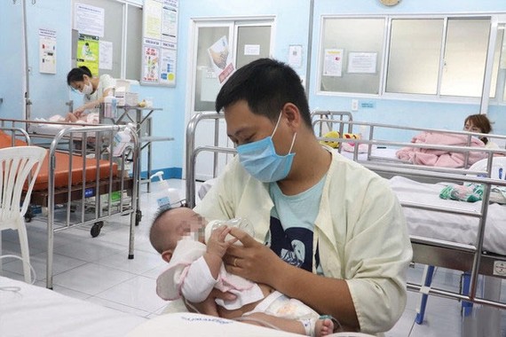 一名年輕爸爸在醫院病房給寶寶餵奶