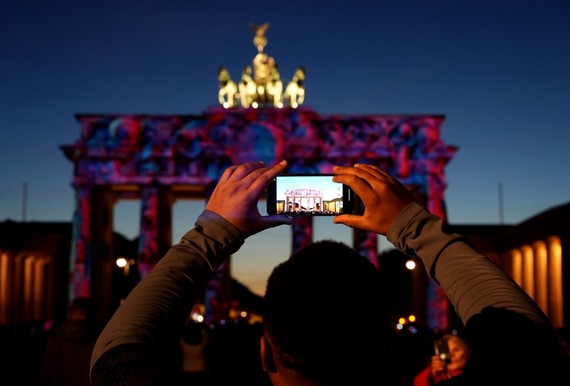 10月7日，在德國柏林，一名遊客拍攝被燈光點亮的勃蘭登堡門。（圖：新華社）